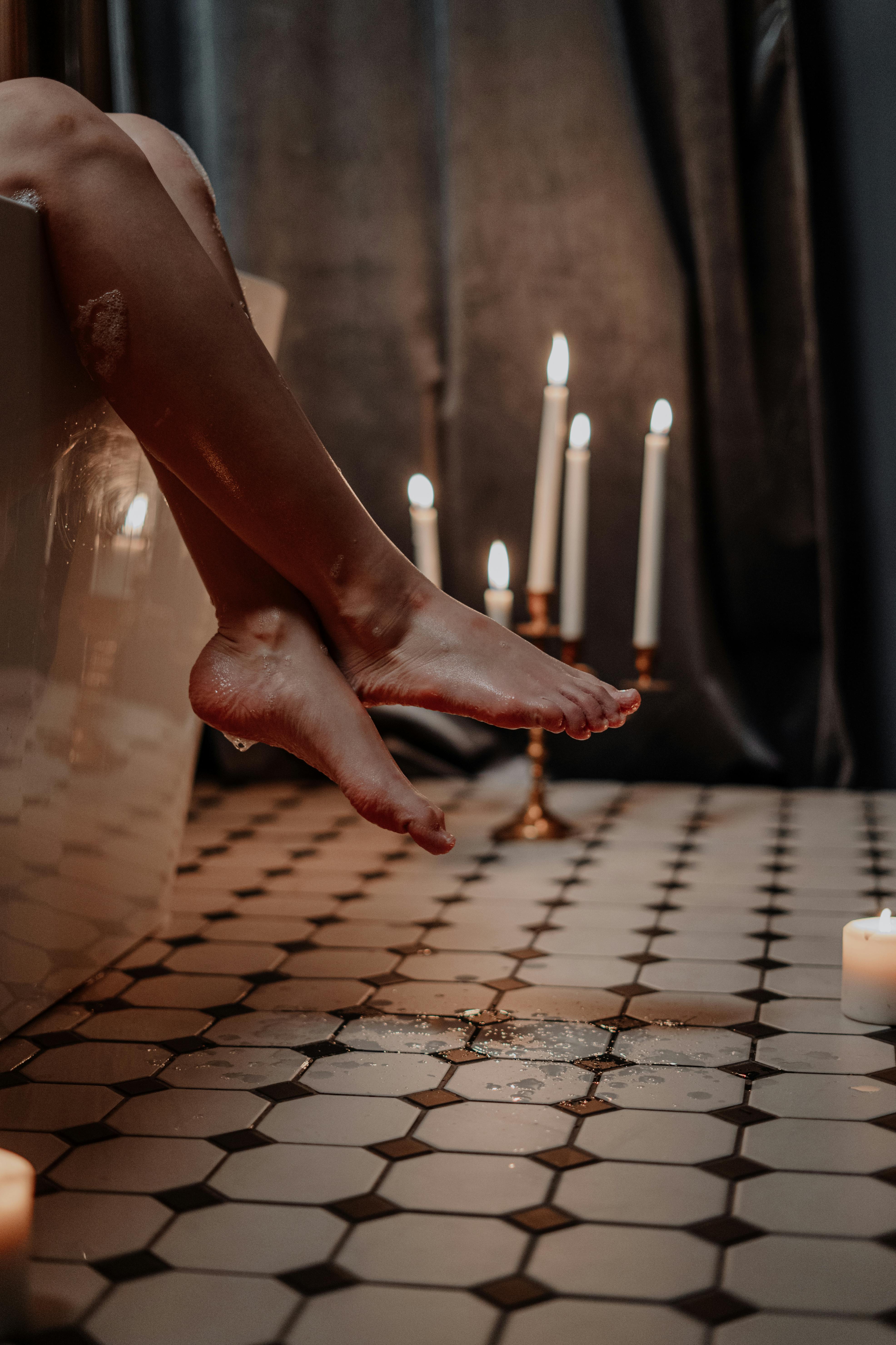 woman feet outside the bath and candles at the corner
